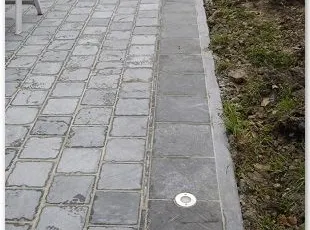 Dallettes en pierre bleue 20/20/2,5 avec contour 30/30/2,5 posées à plein bain mortier sur dalle de béton, bordure en pierre bleue polie 100/25/8 avec un bord arrondi et luminaires encastrés.