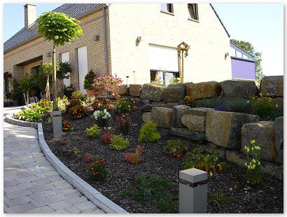 Aménagment privé avec des pavés béton rustique, bordure palissade, rocher décoratif.