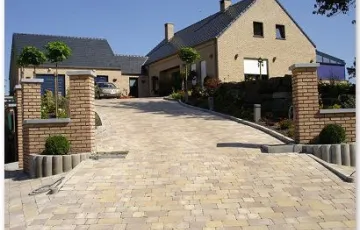 Aménagment privé avec des pavés béton rustique, bordure palissade, rocher décoratif.